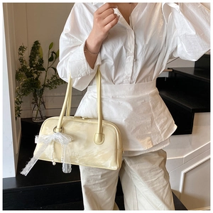 Detail of cream pillow bag showing delicate leather texture and pearl lace bow charm