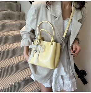 Détail du sac seau jaune pâle avec nœud en dentelle et décoration de chaîne de perles