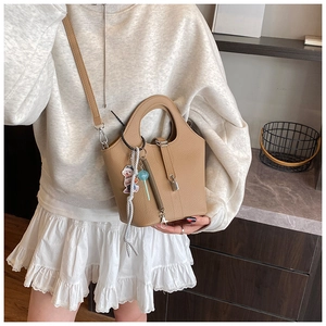 Detail of lychee textured leather bucket bag with metal lock and cute bear charm