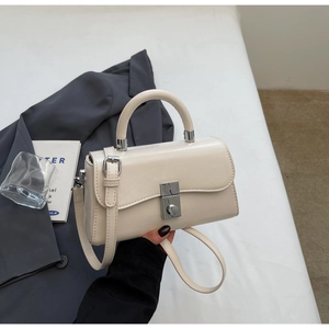 Detail of minimalist cream leather handbag with silver twist lock and round top handle