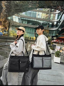 Close-up of black travel bag with dual front zipper pockets in modern outdoor city setting