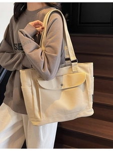 Minimalist beige canvas tote bag for women featuring large front pocket and side compartments