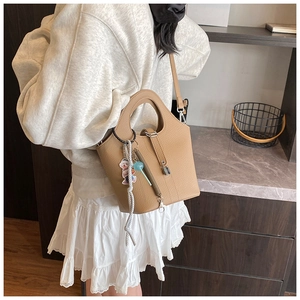 Brown bucket bag featuring a unique hollow handle and stylish lock charm detail