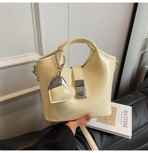 Detail of cream white leather bucket bag featuring silver buckle and heart pendant