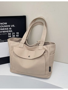 Minimalist beige canvas tote bag with front pocket and double handles for shoulder carry