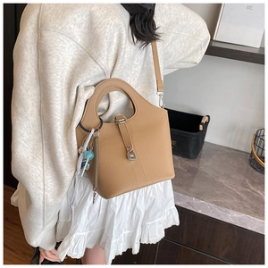 Detail of camel bucket bag showing fine lychee grain texture and metal lock closure