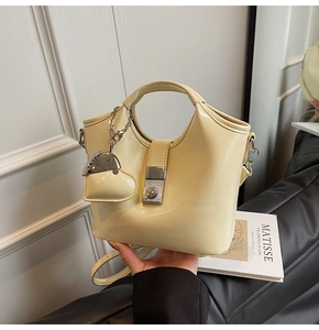 Detail of beige bucket bag featuring silver lock and heart shaped coin purse charm