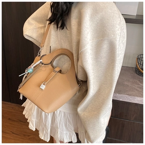Close-up of a light brown litchi pattern leather bucket bag with metal lock and silk scarf