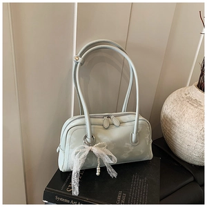 Detail of mint green shoulder bag with lace bow pendant and pearl on black art books