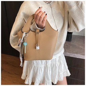 Detail of camel lychee leather bucket bag with silver lock and colorful scarf accessory