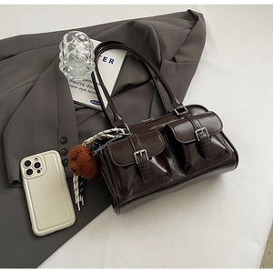 Detail of dark brown glossy PU leather pillow bag with double front pockets and teddy charm