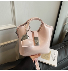 Detail of pink patent leather bucket bag with silver heart charm and adjustable strap
