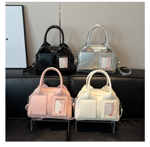 Detail of four Boston bags in black, silver, pink, and white on a leather bench
