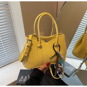 Detailansicht der gelben Eimer-Handtasche aus Leder mit dekorativem Metallverschluss