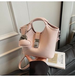 Detailed view of pink handbag with heart pendant and square metal buckle strap