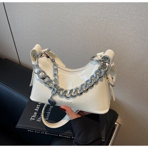 Close-up of creamy white glossy leather shoulder bag with bold silver chain and brand logo