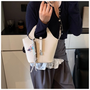 Detail of creamy white pebble leather bucket bag with silver lock and bear charm