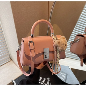 Detailed view of pink leather bucket bag with silver metal lock and teddy bear charm