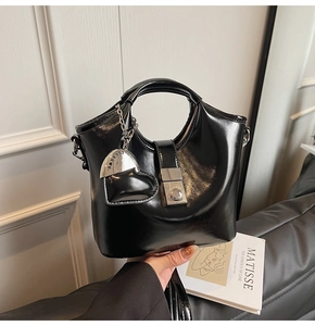 Detailed view of black patent leather bucket bag with silver buckle and heart charm