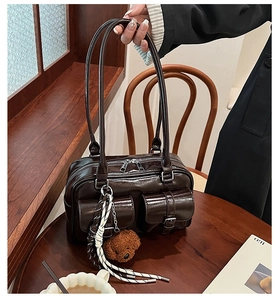 Detail of dark brown leather pillow bag with cute bear charm and woven tassel detail