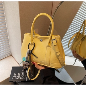 Detail der gelben Leder-Beuteltasche mit Metallschnalle und süßem Bären-Anhänger
