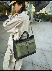 Outdoor shot of olive green and black travel tote bag with multiple zip pockets