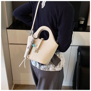 Detail of lychee textured bucket bag with metal lock and round handle worn crossbody