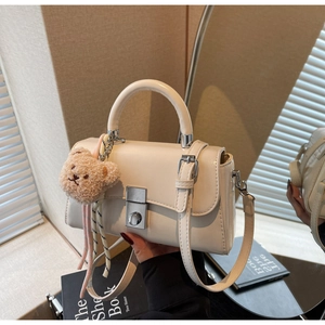 Detail of cream white leather mini tote with silver lock and brown plush bear charm
