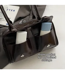 Detail of glossy brown handbag featuring double front pockets and silver magnetic snaps