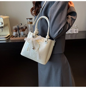 Détail du sac seau blanc crème avec nœud en dentelle, perles et pendentif en cœur