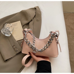 Detailed view of pink patent leather half-moon bag with silver chain on white sheets