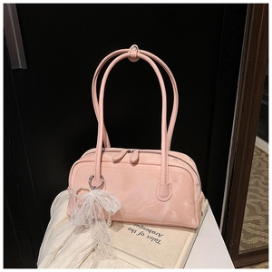 Detail of pink shoulder bag with lace and pearl charm on white fabric and vintage book