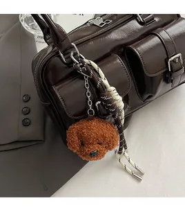 Close-up of dark brown glossy bag with two front pockets and a cute plush dog charm