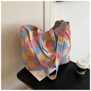Close-up of a large capacity plaid tote bag in red, blue and yellow on a wooden desk