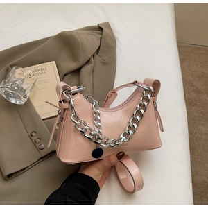 Detailed shot of pink patent leather shoulder bag with glossy finish and silver chain strap