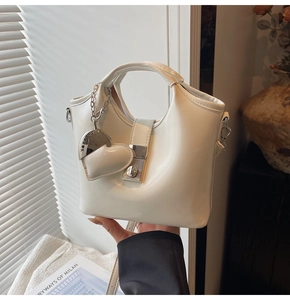 Detail of off-white bucket bag featuring heart pendant and silver metal hardware