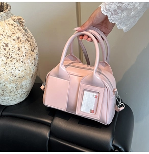 Dettaglio borsa Boston in vernice rosa chiaro con fessura per carte e manici