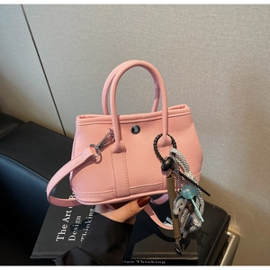 Detail der rosa Bucket Bag aus genarbtem Leder mit Bärenanhänger und Silber-Druckknopf