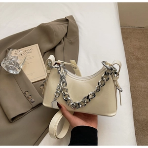 Detail of cream glossy leather handbag with chunky silver chain and metal charm