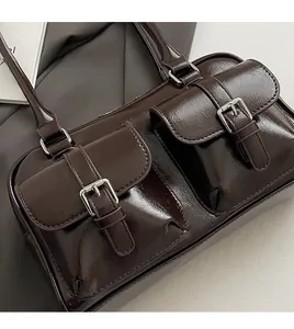 Detailed close-up of dark brown glossy pillow bag featuring dual front pockets and silver buckles