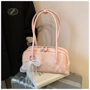 Detail of pink baguette bag with lace bow, pearl charm and dual zippers on books