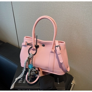 Detail der rosa Bucket-Bag aus Leder mit Narbenstruktur, Silberschnalle und Bär-Anhänger