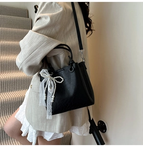 Détail d'un sac seau noir avec charme en perle et dentelle sur un escalier moderne