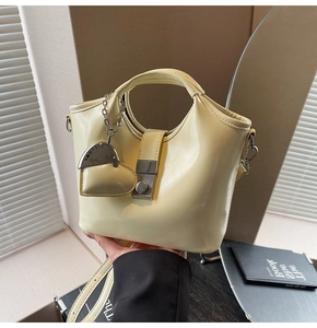 Detail of cream bucket bag showing silver clasp, heart charm and polished leather texture