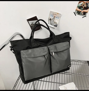 Detail of black nylon travel tote bag with grey zip pockets on a metal shelf