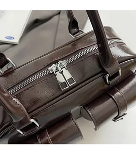 Detail of silver dual zippers and glossy dark brown leather texture on a tote bag
