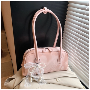 Detailed macro view of pink patent leather handbag with pearl bow and lace charm