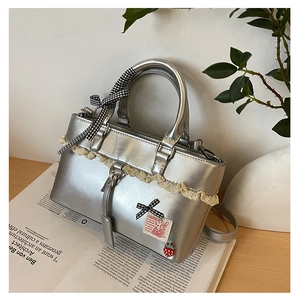 Detail of silver lace handbag with checkered bow and strawberry pin on book