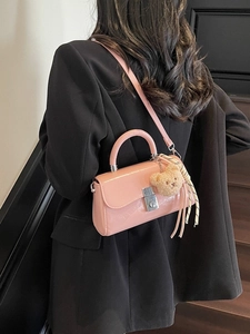 Pink glossy patent leather bucket bag with silver lock and plush bear charm on model