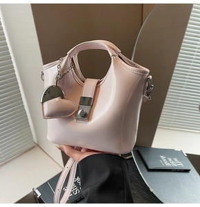 Detail of light pink patent leather bucket bag with silver heart charm and metal lock